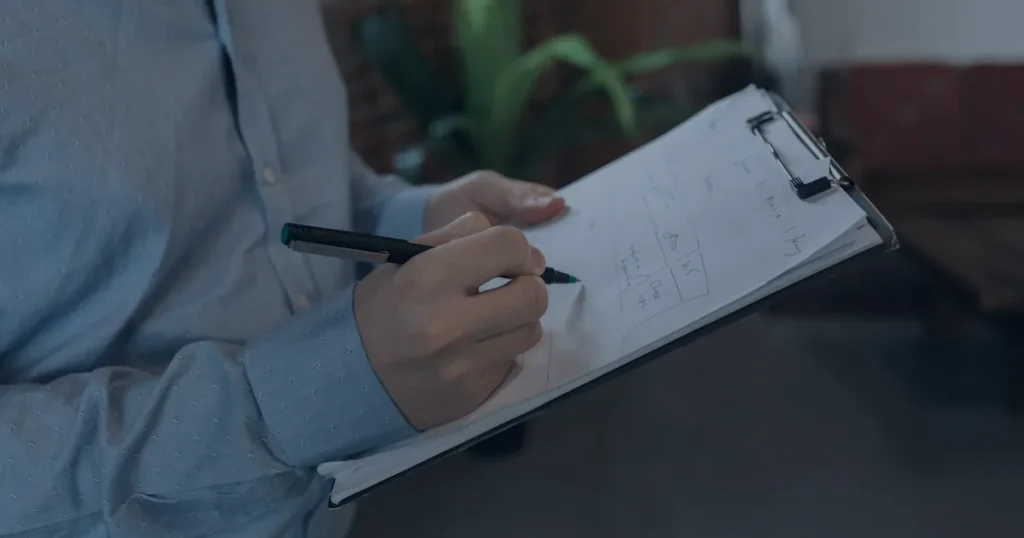 Mão preenchendo lista em prancheta ilustrando um checklist de segurança digital para a empresa