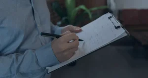 Mão preenchendo lista em prancheta ilustrando um checklist de segurança digital para a empresa