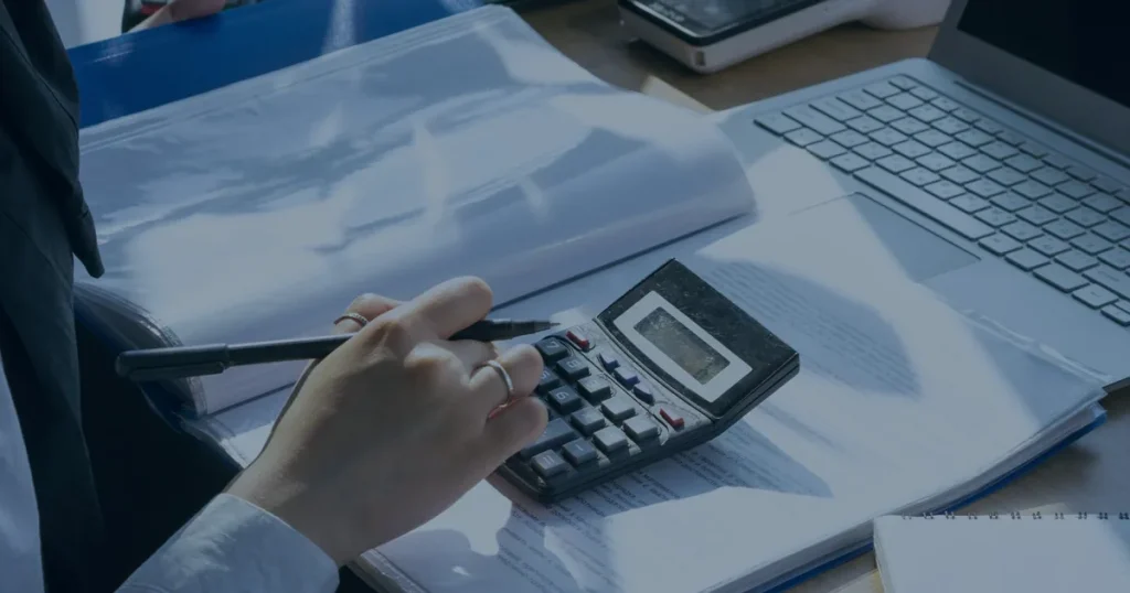 Calculadora e documentos em mesa ilustrando os custos ocultos da falta de manutenção em TI