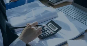 Calculadora e documentos em mesa ilustrando os custos ocultos da falta de manutenção em TI