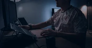 Pessoa em escritório escuro usando notebook ilustrando o golpe de engenharia social