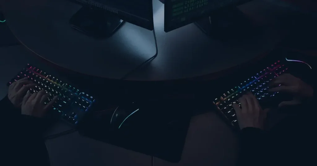 Mãos em teclados na penumbra ilustrando a engenharia social e como prevenir o golpe