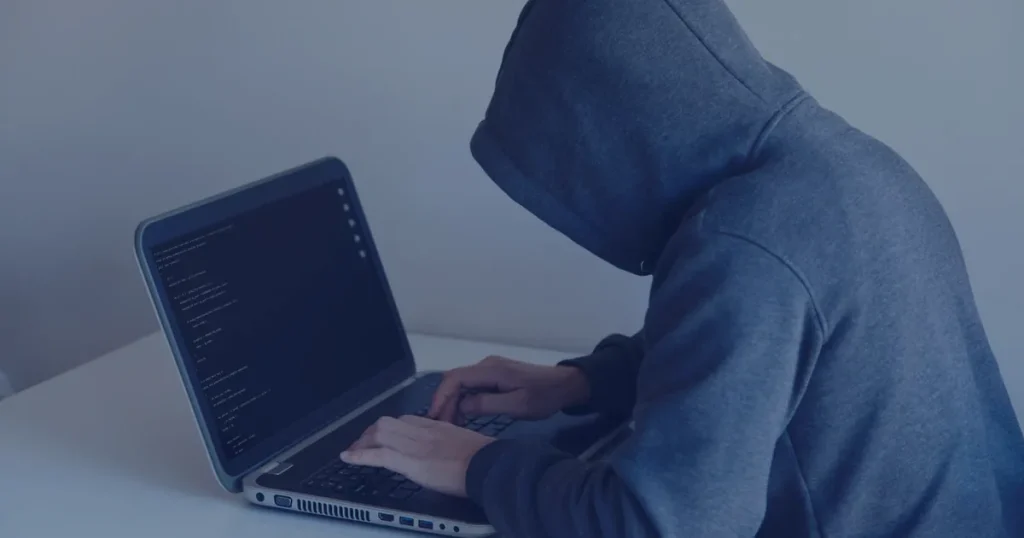 Figura encapuzada em notebook ilustrando como proteger operações contra ataques de ransomware