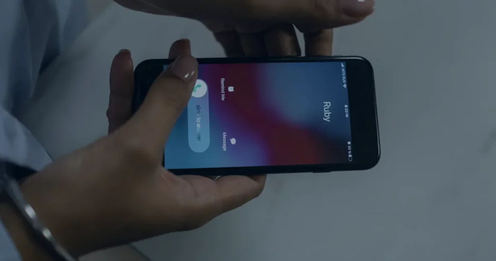Mão com smartphone recebendo chamada ilustrando os riscos da engenharia social