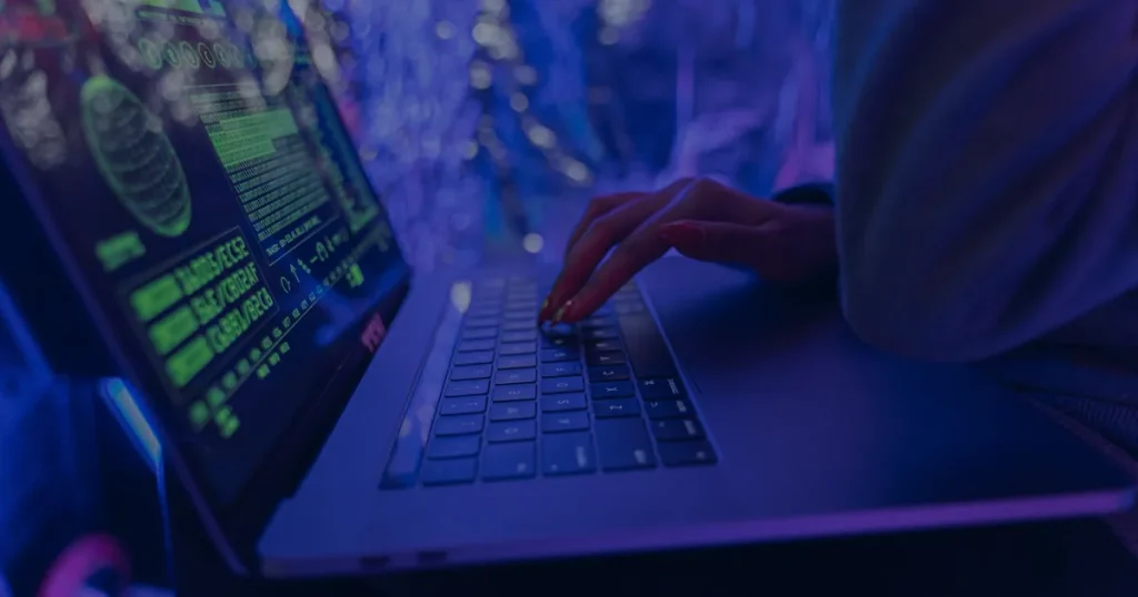 Mãos digitando em notebook azul ilustrando como criar senhas realmente seguras