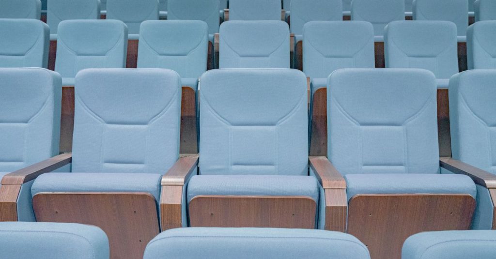 Auditório moderno com poltronas azuis pronto para evento de inovação
